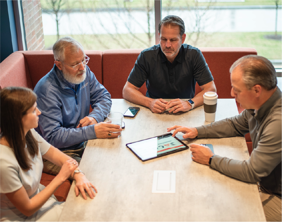 Professional business advisors meeting with clients around conference table discussing strategy and growth plans